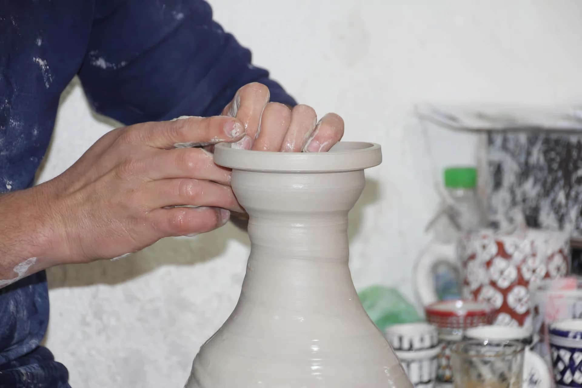 Visitante vestido para trabajo artesanal en mesa de cerámica en Fez